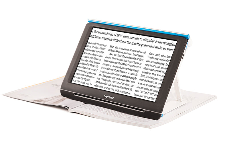 Front facing view of the portable Optelec Compact 10 With Speech displaying enlarged text on it's screen resting on top of an open magazine.