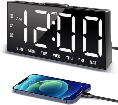 Digital Alarm Clock with Large Display.  Perfect for anyone, with low vision who may have difficulties seeing smaller clocks or trouble with clocks that do not have a contrasting color. shown here is a black clock with big and bold white numbers and letters with a black contrasting background on the clock.  It shows that it is tethered to a black cable and connected to a mobile device.