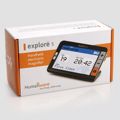 Humanware Explore 5 electronic magnifier in manufacturer packaging. The box is white and orange and features a close up of the device which features a high definition LCD screen with physical buttons that include a bright orange camera button and buttons to increase and decrease size. The device is angled and can stand up on its own for easy viewing.