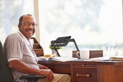 A black man sitting at a desk using the Explore 8 in the stand.